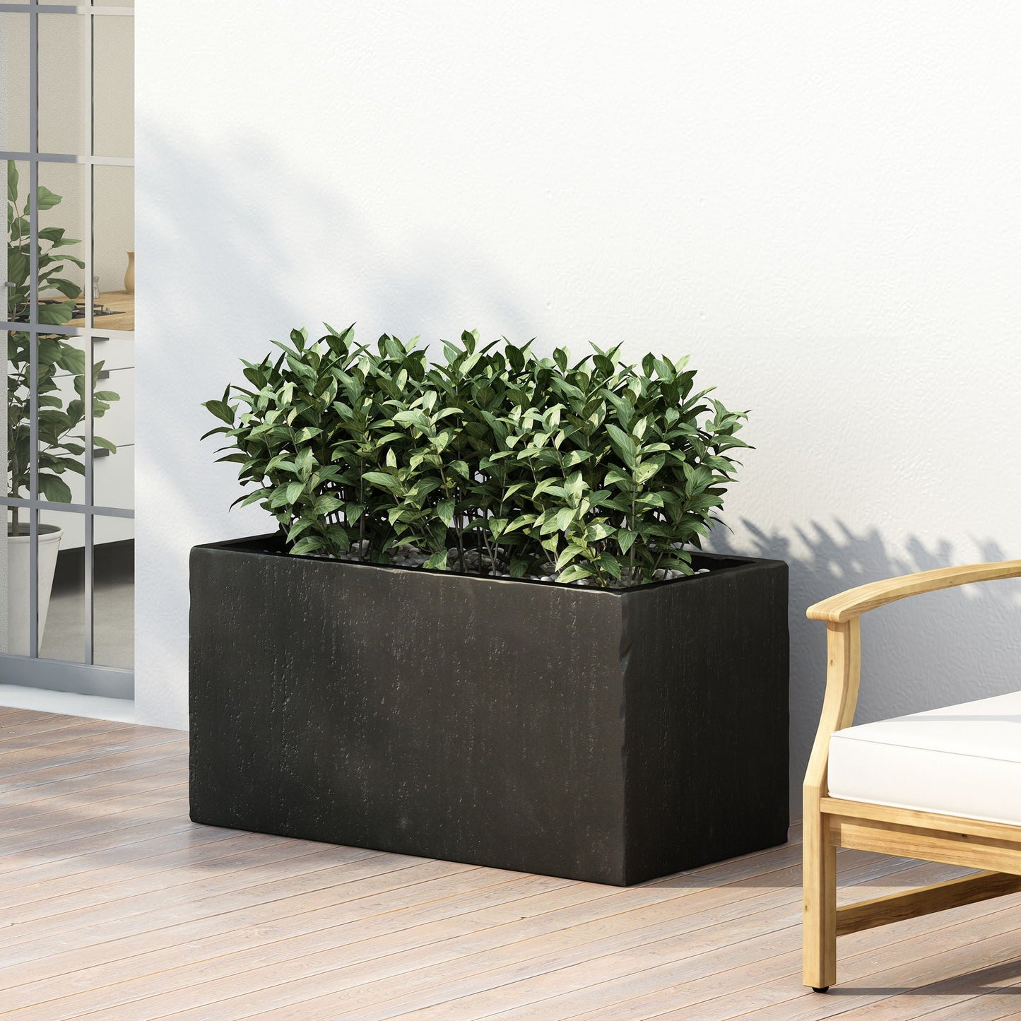 Black rectangular planter with green plants on a wooden deck next to a chair.