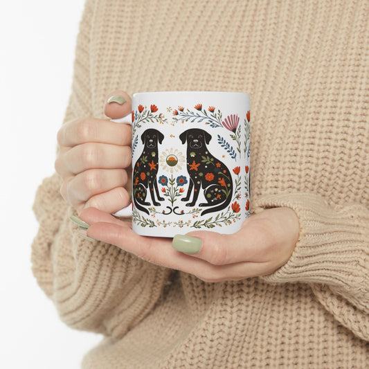 Person holding a mug with black labrador design and floral elements