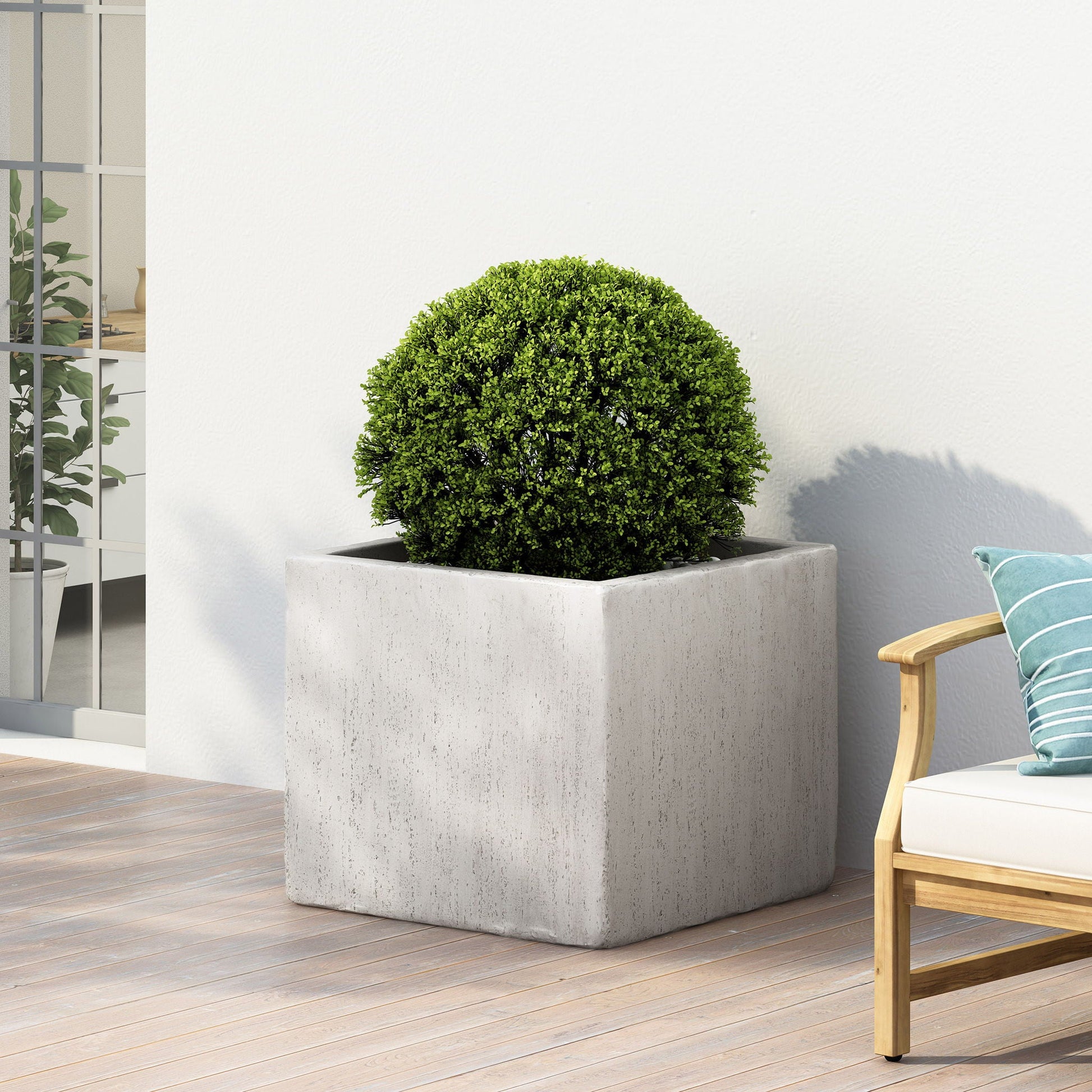 Square concrete planter with a green bush on a wooden deck