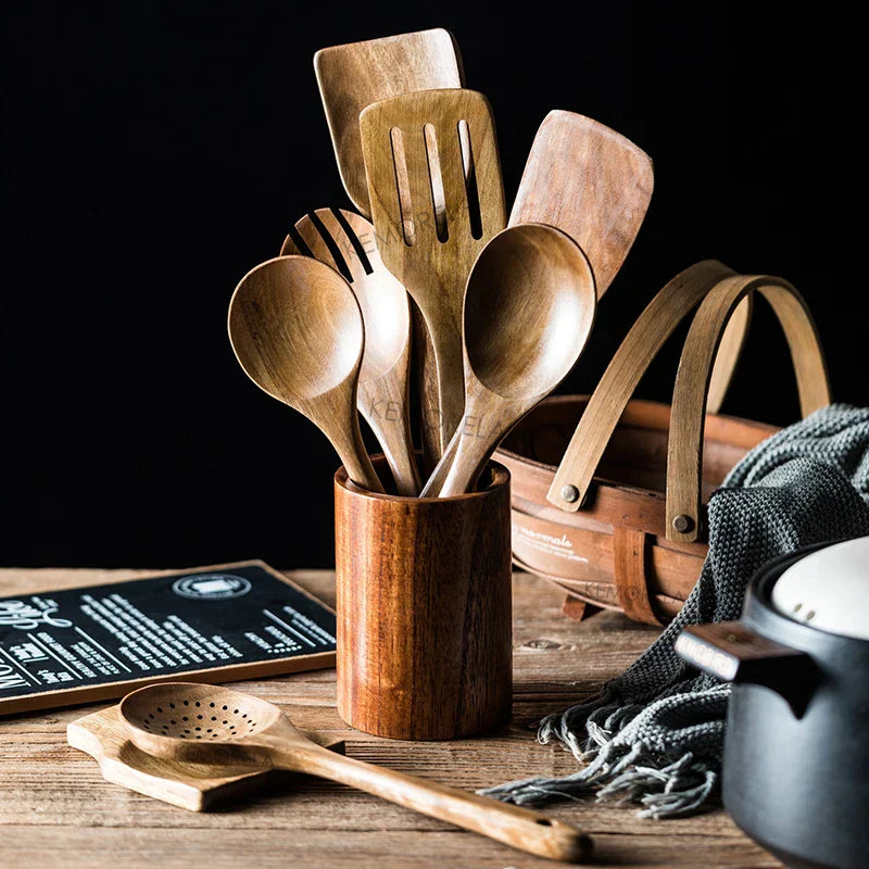 Wooden kitchen utensils in a wooden holder on a rustic wooden surface with a dark background.