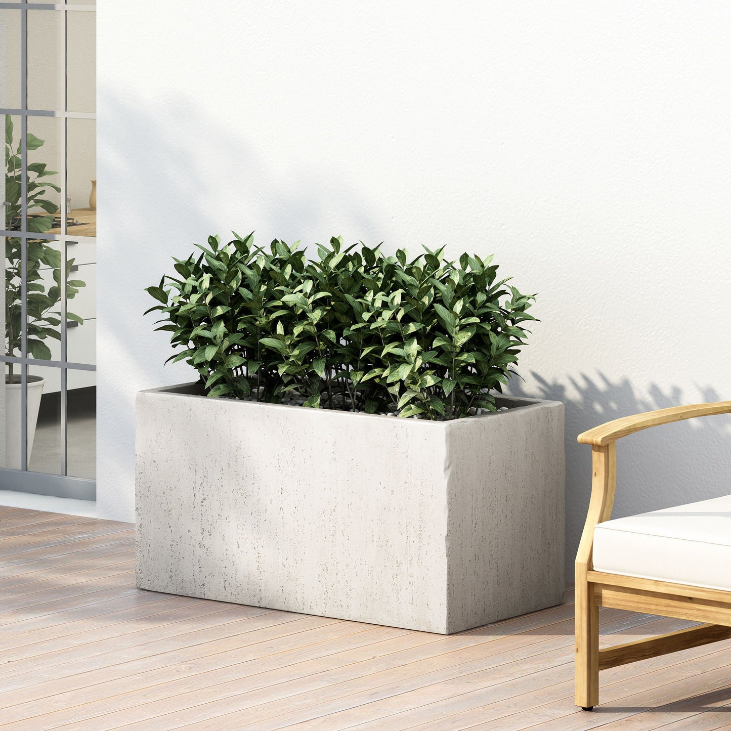 Rectangular concrete planter with green plants on a wooden deck next to a chair.