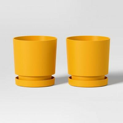 Two yellow plant pots on a light gray background