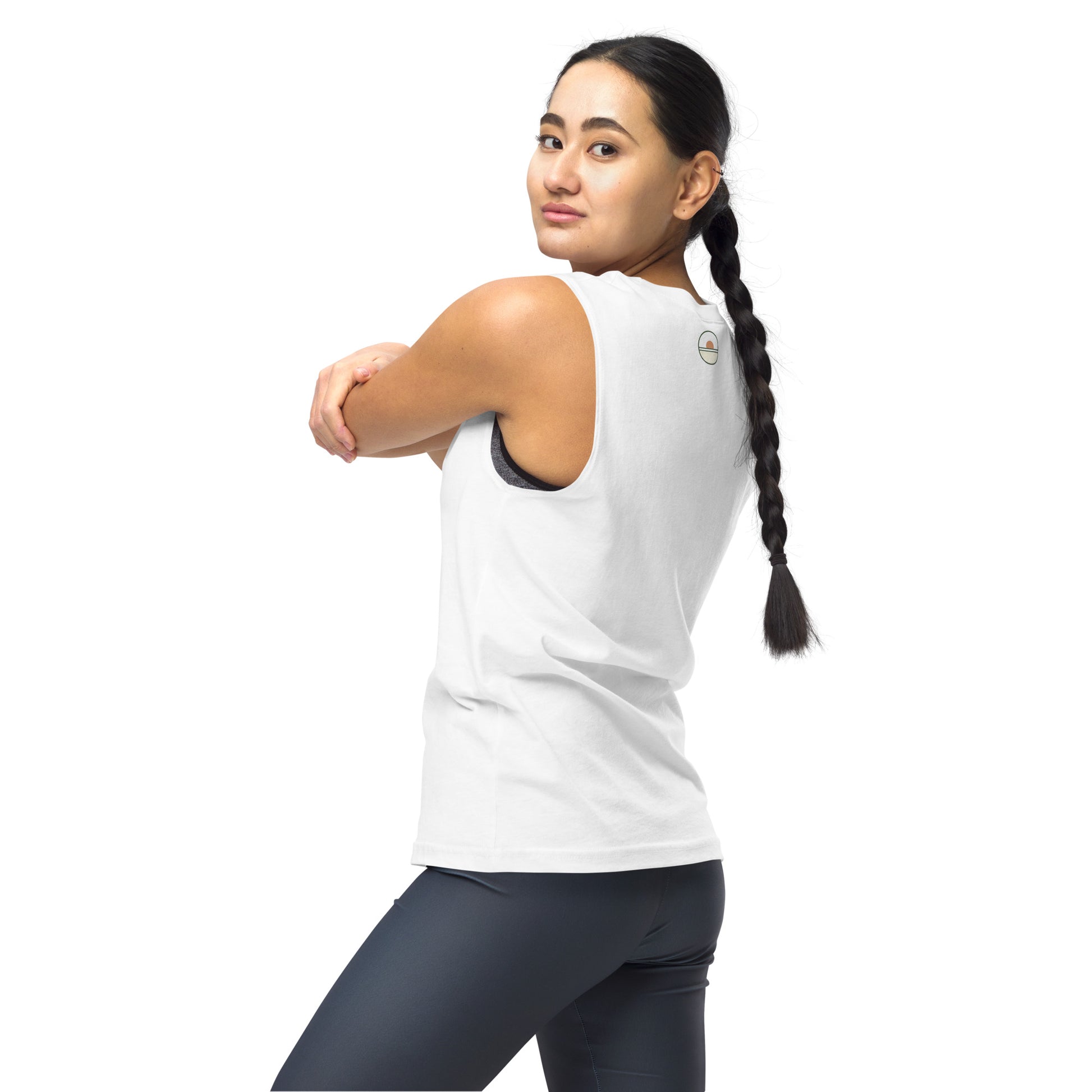 Woman in a white tank top and dark leggings standing against a white background